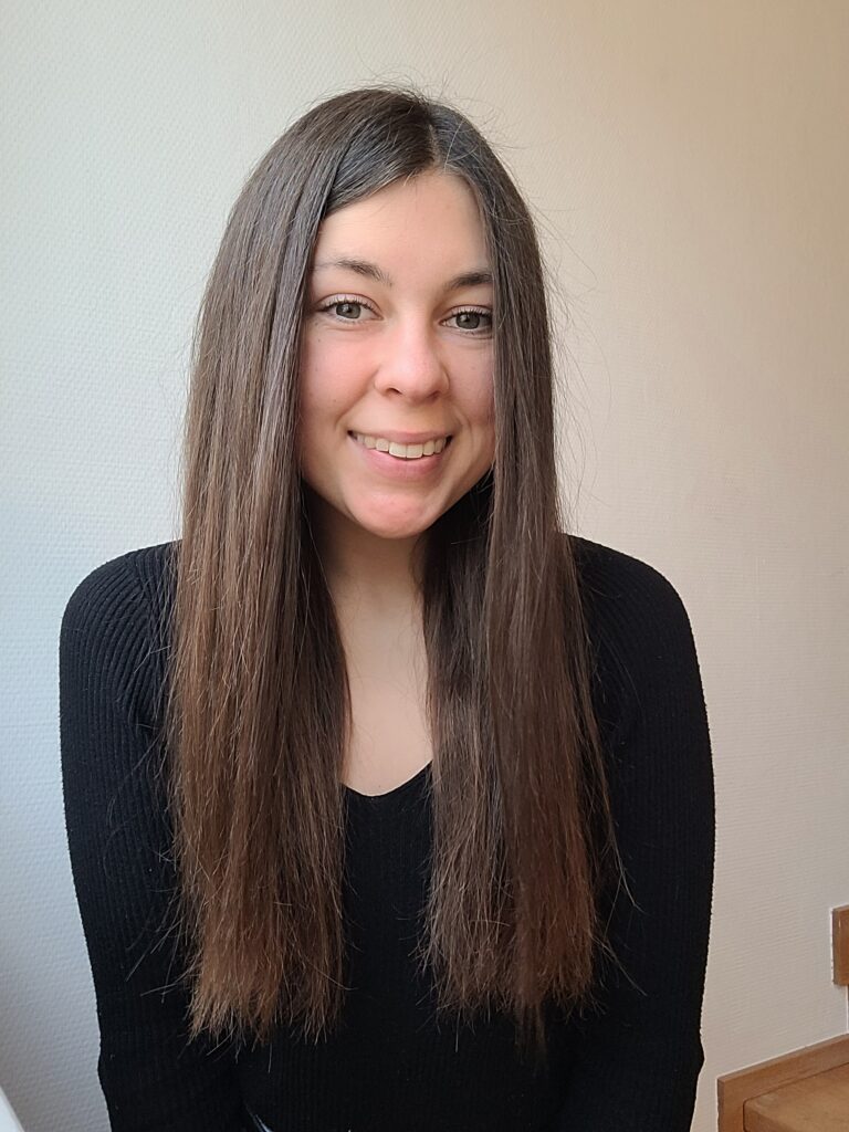Porträt von Aline, junge Frau mit langen dunklen Haaren im schwarzen Pullover
